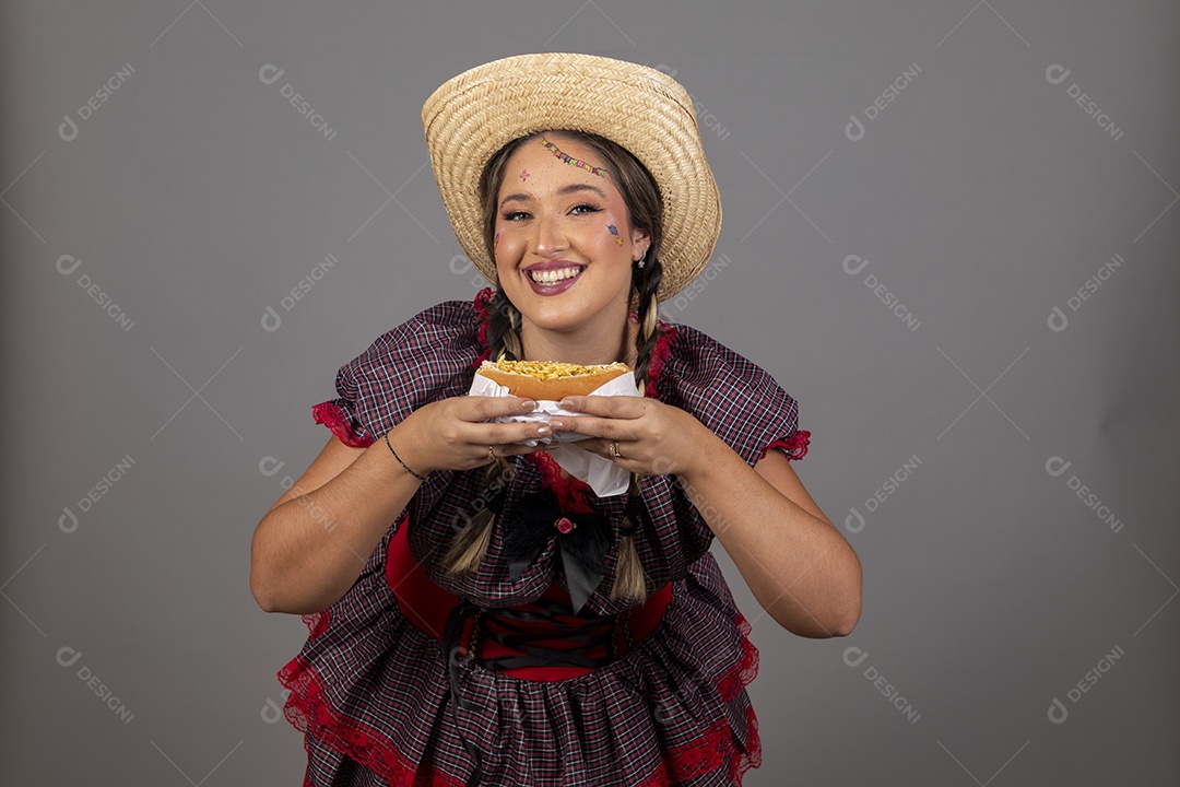 Mulher linda jovem usando roupas típicas festa junina sobre fundo isolado se alimentando