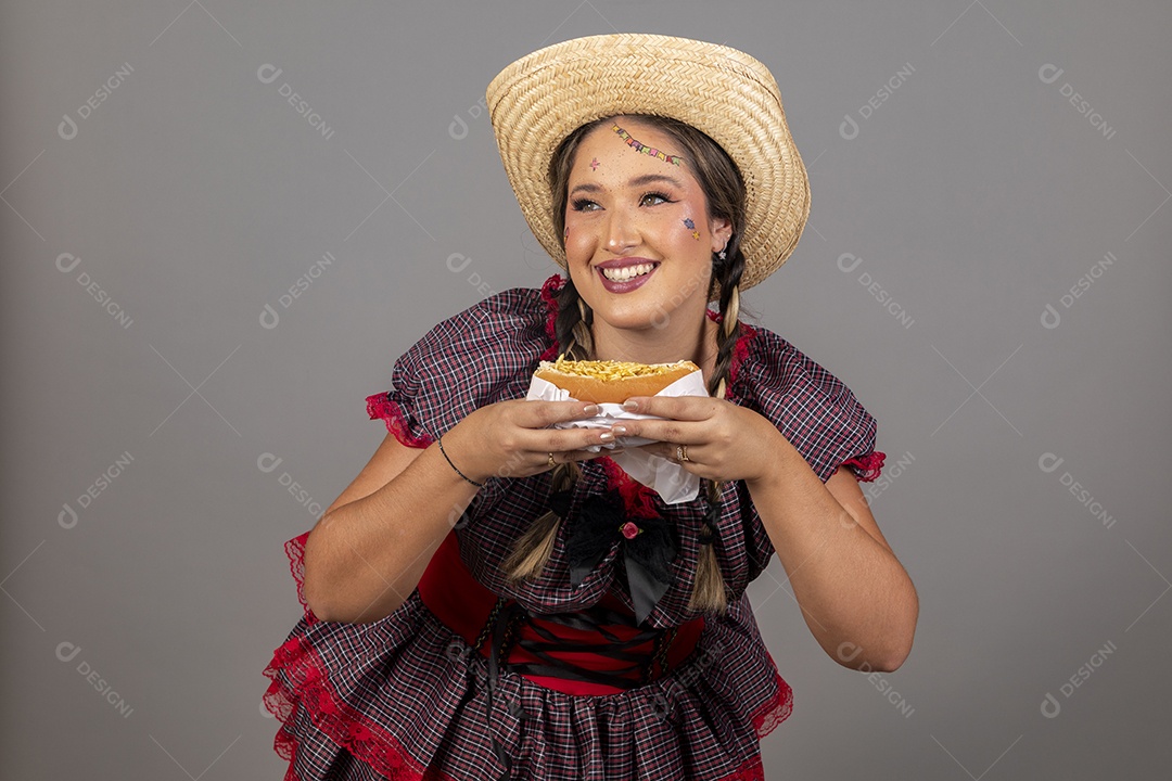 Mulher linda jovem usando roupas típicas festa junina sobre fundo isolado se alimentando