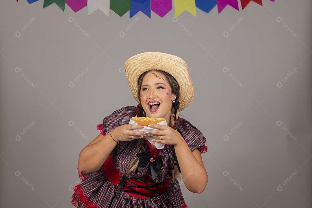 Mulher linda jovem usando roupas típicas festa junina sobre fundo isolado se alimentando