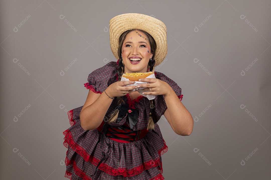 Mulher linda jovem usando roupas típicas festa junina sobre fundo isolado se alimentando