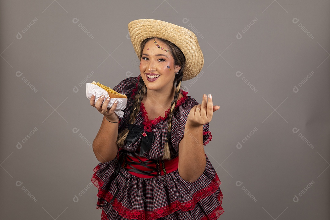 Mulher linda jovem usando roupas típicas festa junina sobre fundo isolado se alimentando