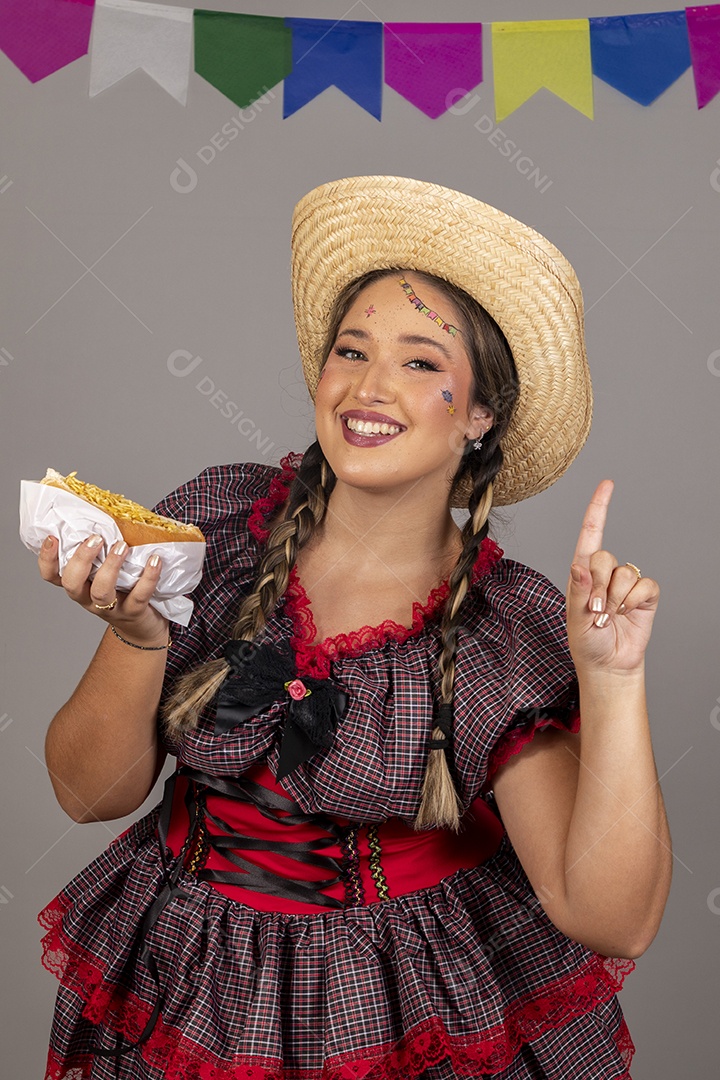 Mulher linda jovem usando roupas típicas festa junina sobre fundo isolado se alimentando