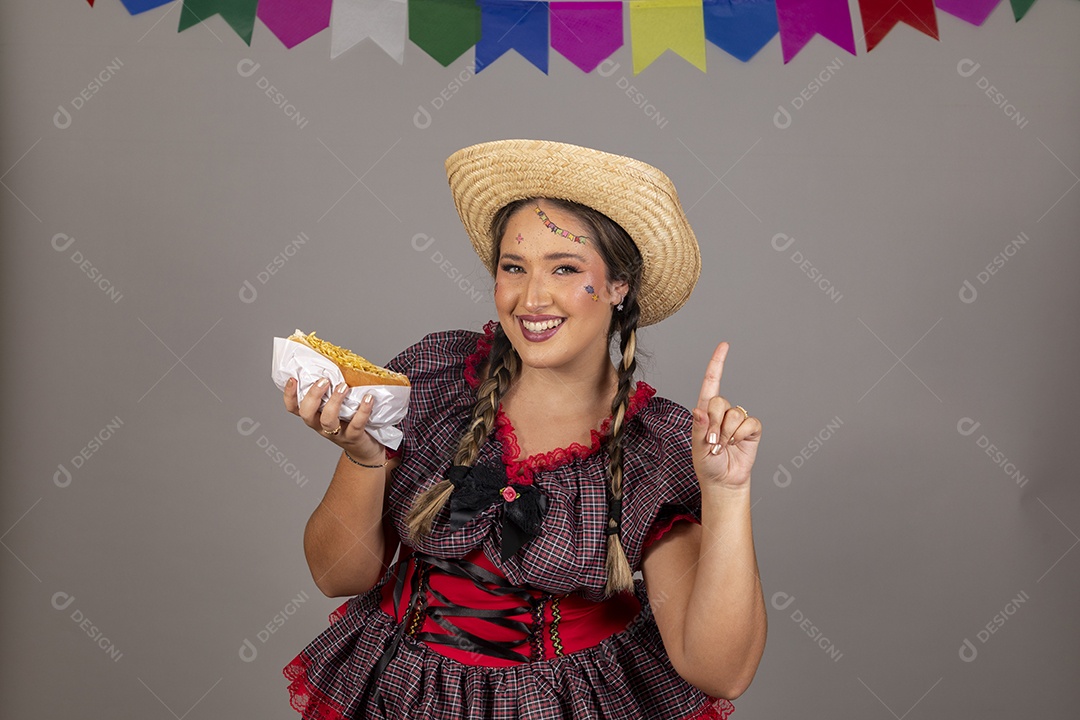 Mulher linda jovem usando roupas típicas festa junina sobre fundo isolado se alimentando