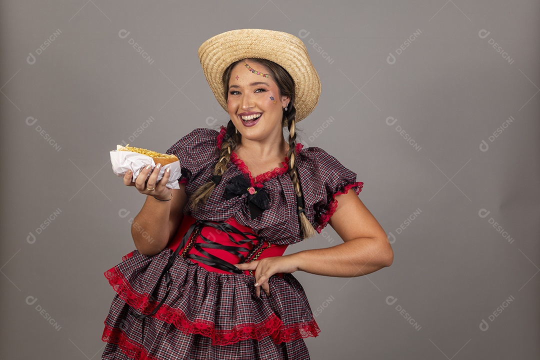 Mulher linda jovem usando roupas típicas festa junina sobre fundo isolado se alimentando