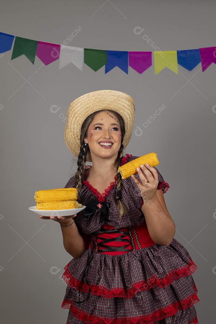 Mulher linda jovem usando roupas típicas festa junina sobre fundo isolado se alimentando
