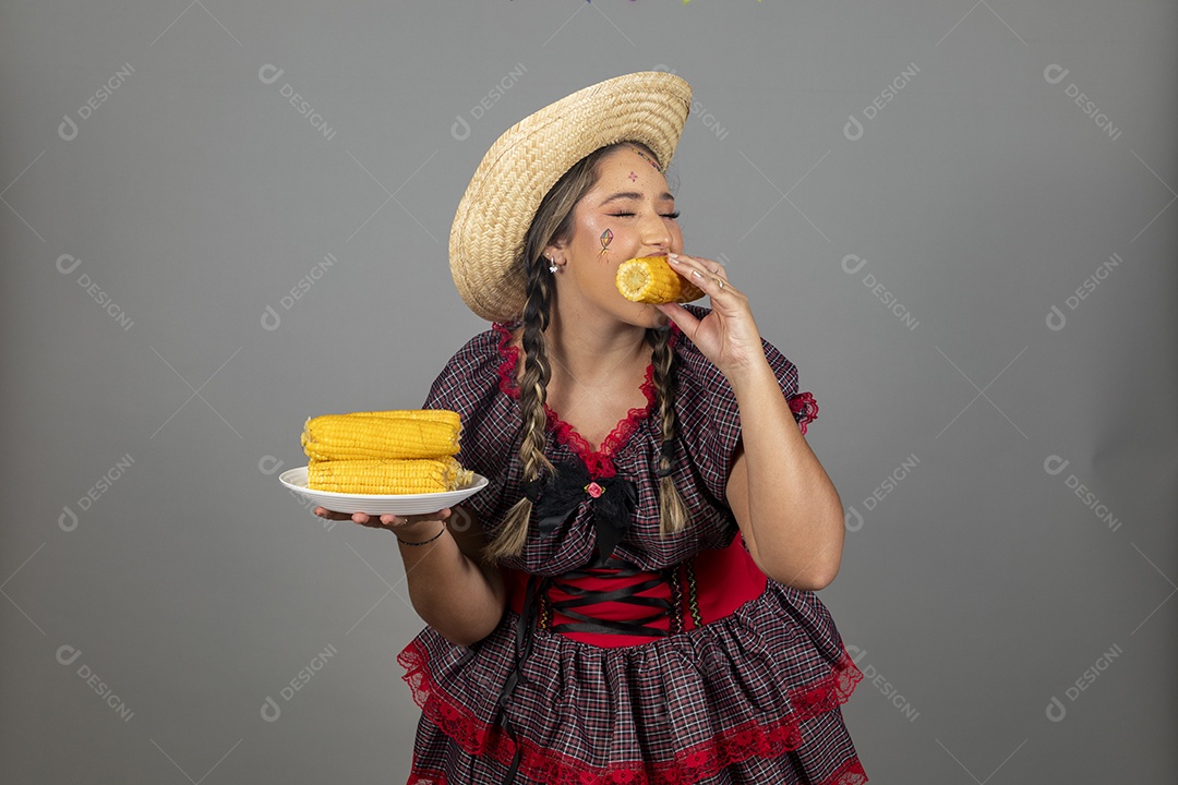 Mulher linda jovem usando roupas típicas festa junina sobre fundo isolado se alimentando