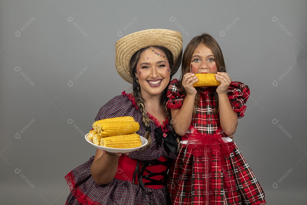 Mãe jovem usando roupas típicas festa junina sobre fundo isolado ao lado de sua filha