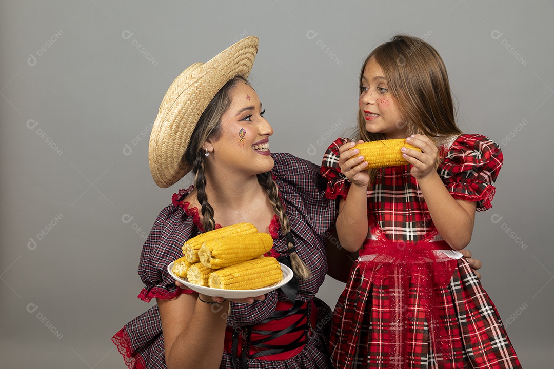 Mãe jovem usando roupas típicas festa junina sobre fundo isolado ao lado de sua filha
