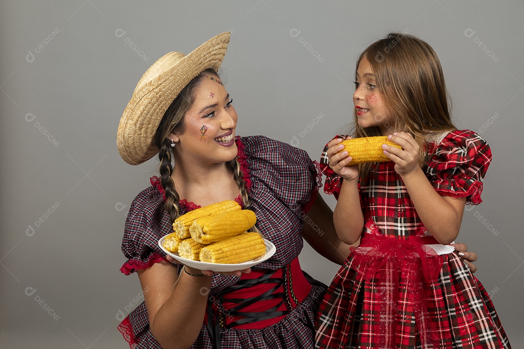 Mãe jovem usando roupas típicas festa junina sobre fundo isolado ao lado de sua filha