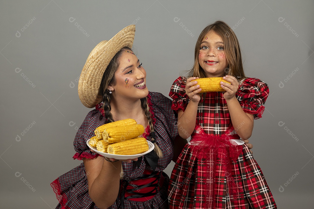 Mãe jovem usando roupas típicas festa junina sobre fundo isolado ao lado de sua filha