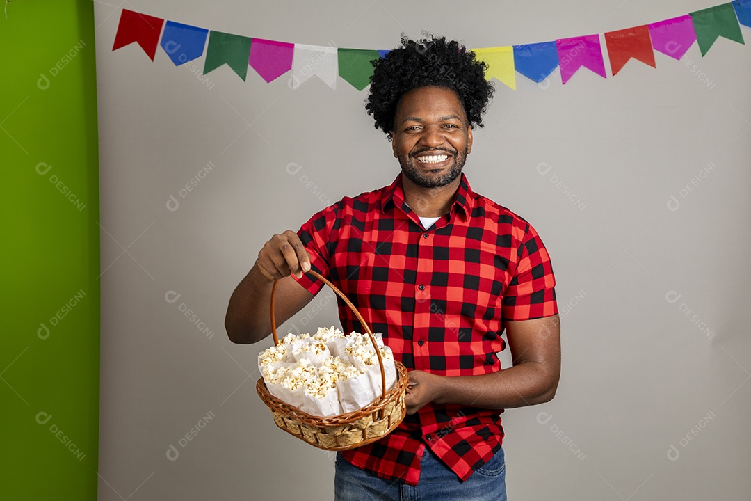 Homem jovem usando roupas típicas festa junina sobre fundo isolado se alimentando