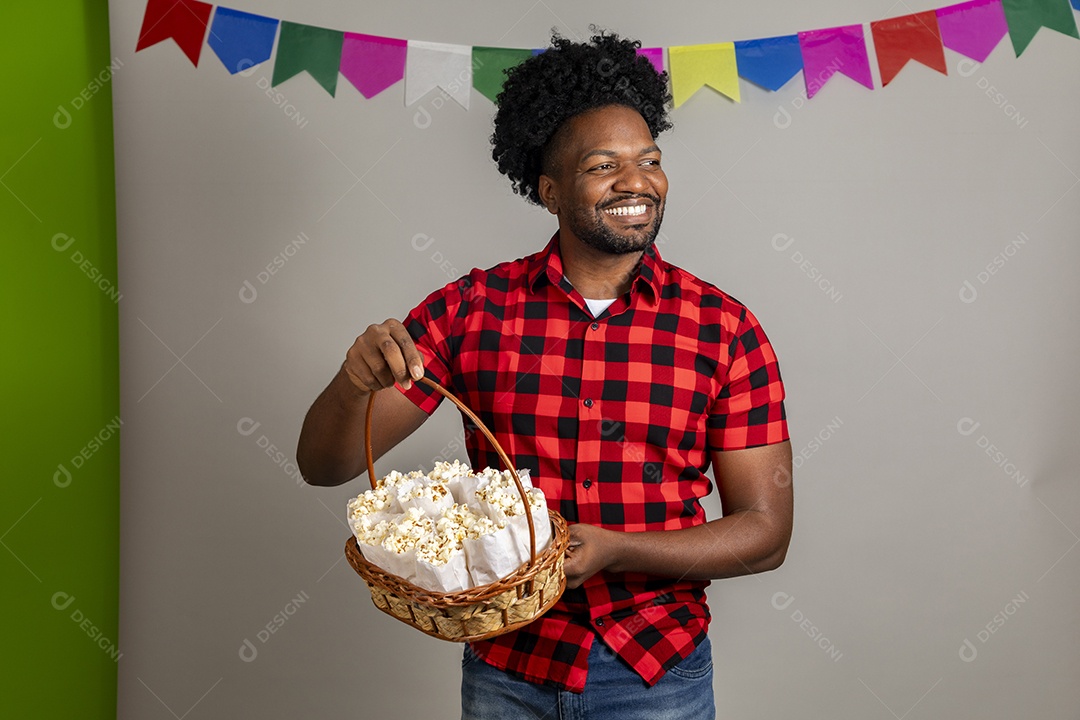 Homem jovem usando roupas típicas festa junina sobre fundo isolado se alimentando