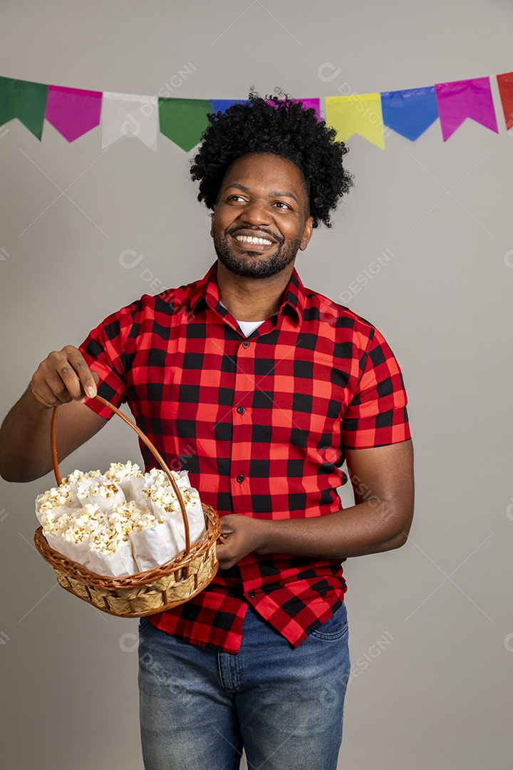 Homem jovem usando roupas típicas festa junina sobre fundo isolado se alimentando