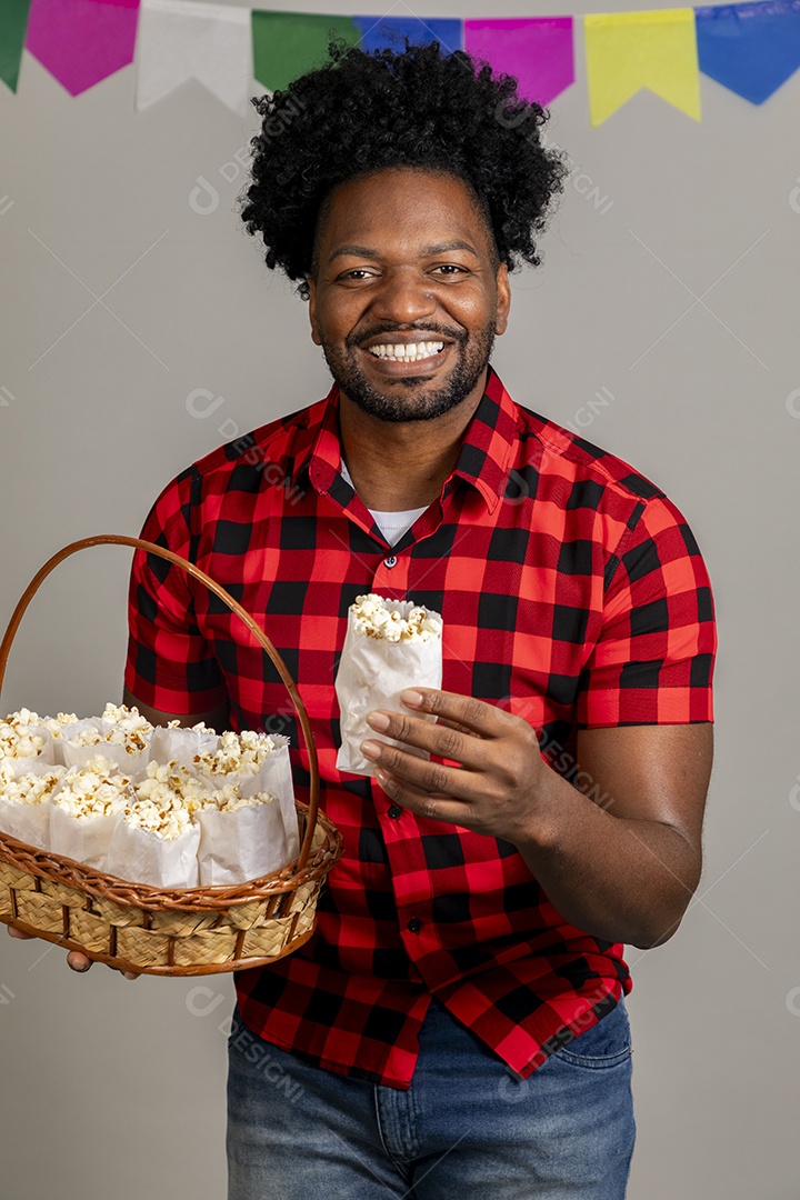 Homem jovem usando roupas típicas festa junina sobre fundo isolado se alimentando