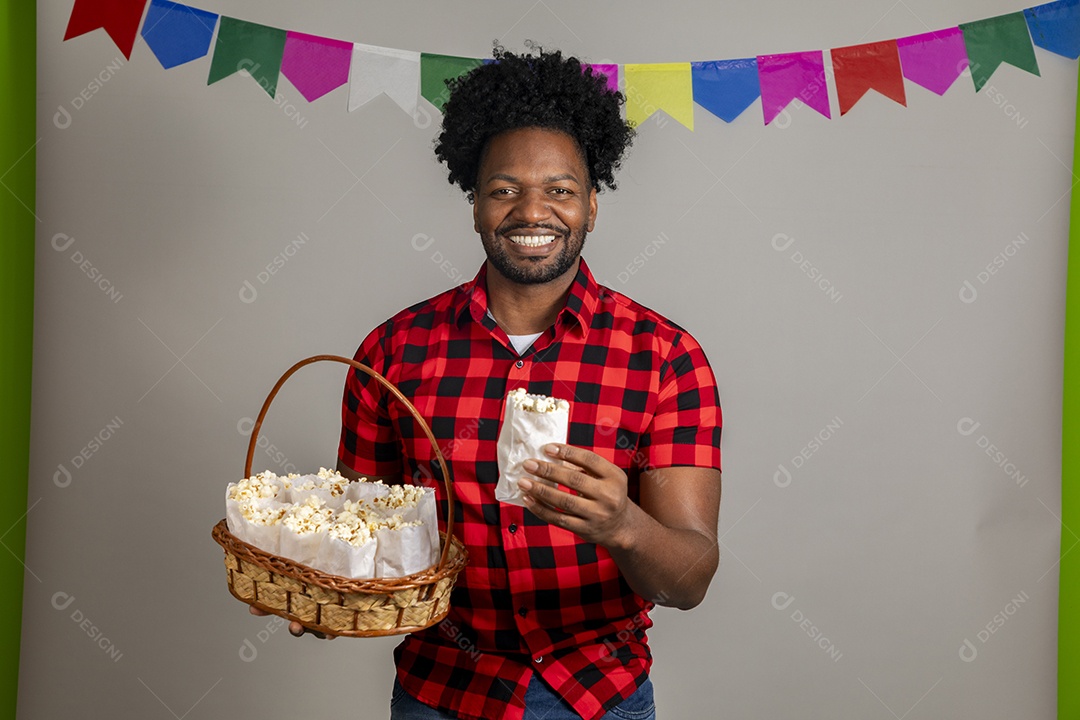 Homem jovem usando roupas típicas festa junina sobre fundo isolado se alimentando
