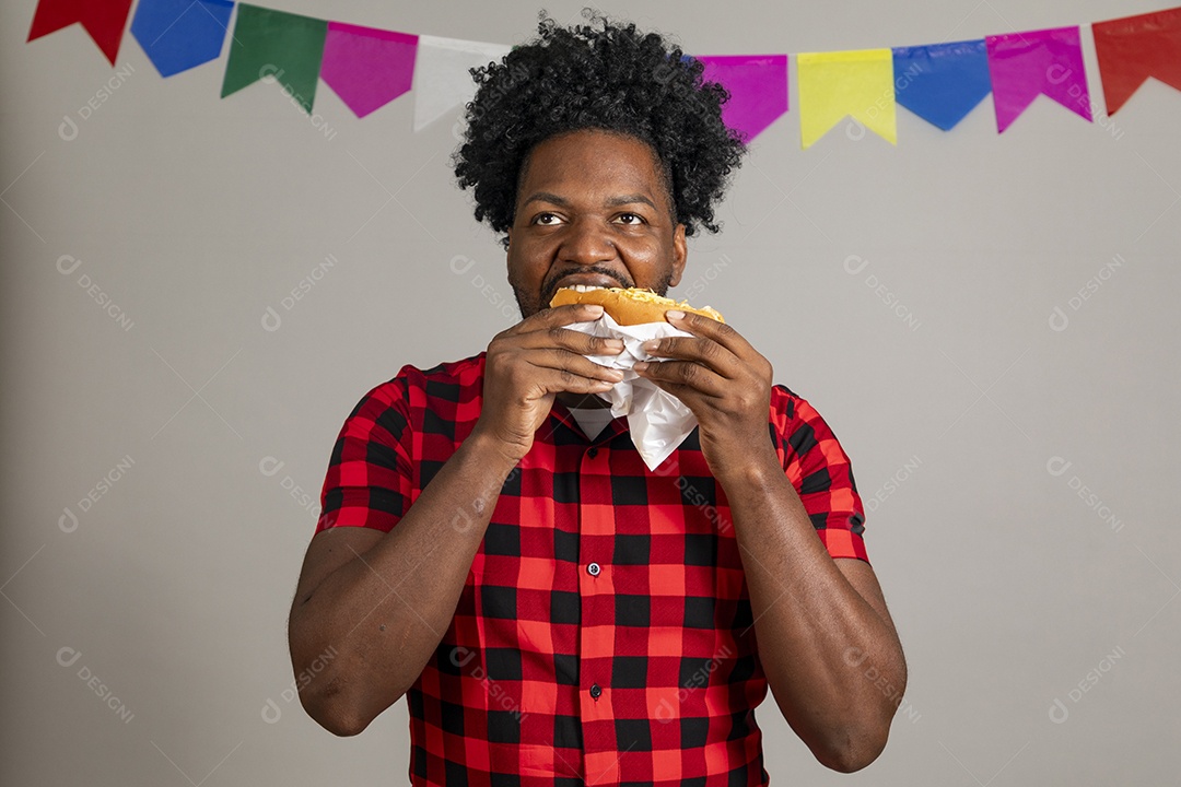 Homem jovens usando roupas típicas festa junina sobre fundo isolado se alimentando