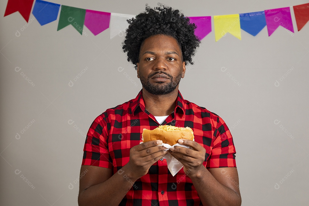 Homem jovens usando roupas típicas festa junina sobre fundo isolado se alimentando
