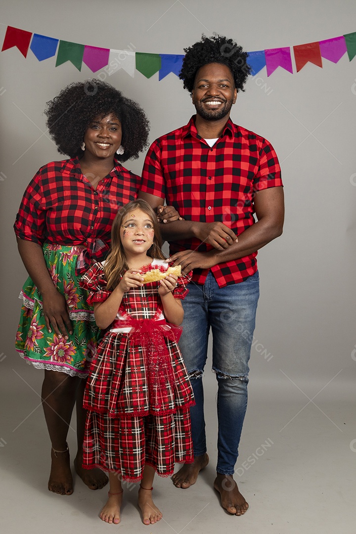 Lindo casal de jovens ao lado de sua filha celebrando festa junina usando roupas típicas