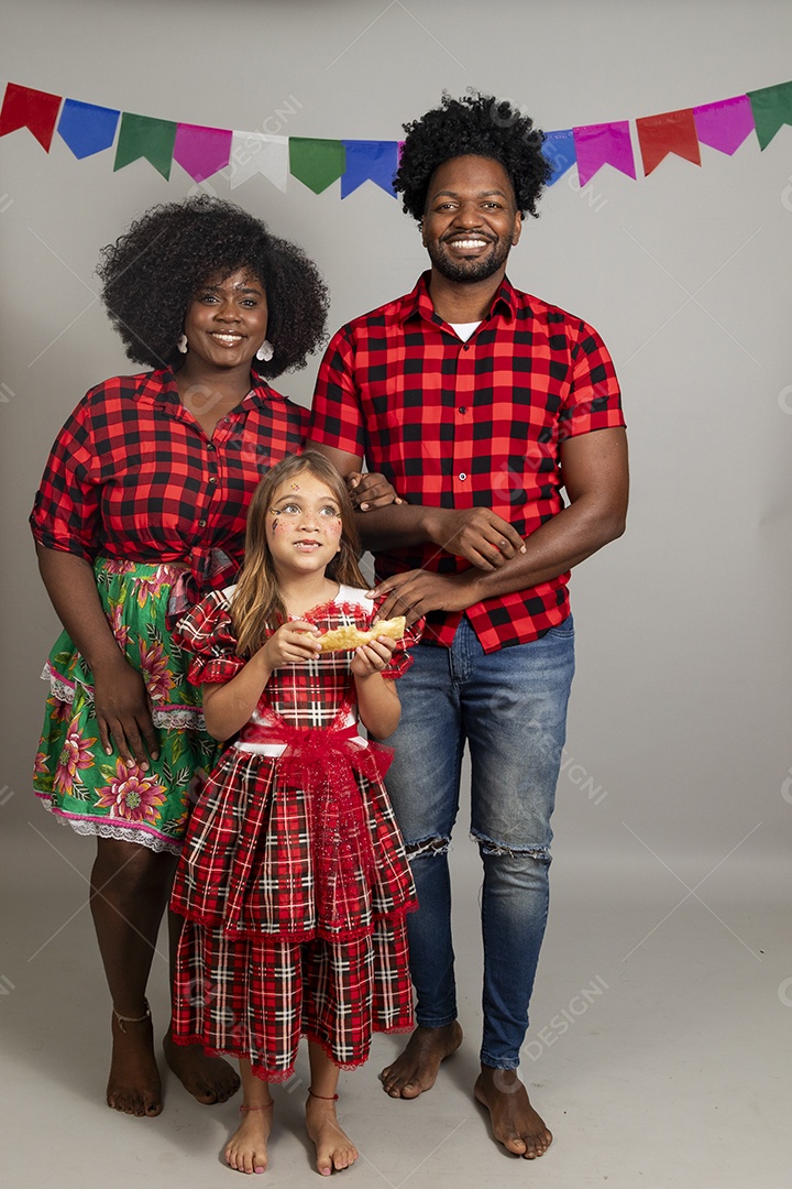 Lindo casal de jovens ao lado de sua filha celebrando festa junina usando roupas típicas
