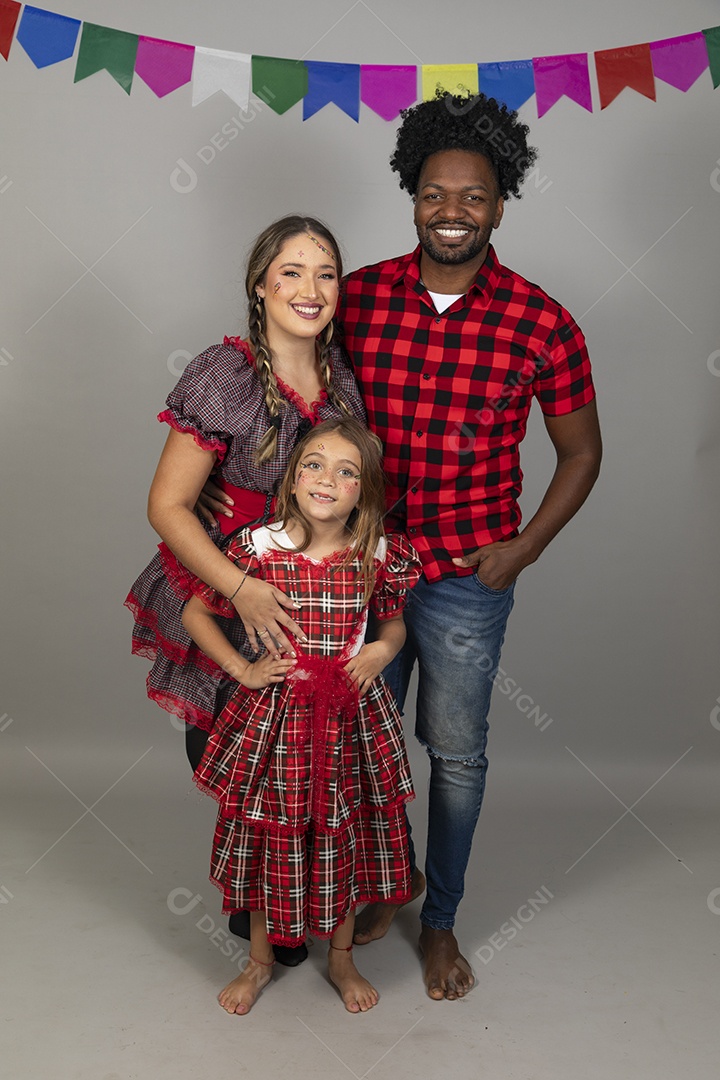 Lindo casal de jovens ao lado de sua filha celebrando festa junina usando roupas típicas