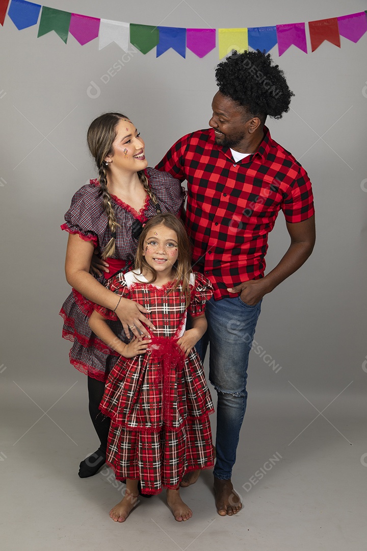 Lindo casal de jovens ao lado de sua filha celebrando festa junina usando roupas típicas