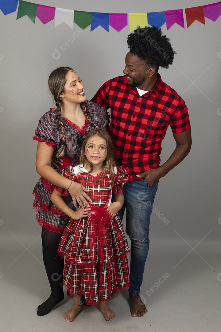 Lindo casal de jovens ao lado de sua filha celebrando festa junina usando roupas típicas