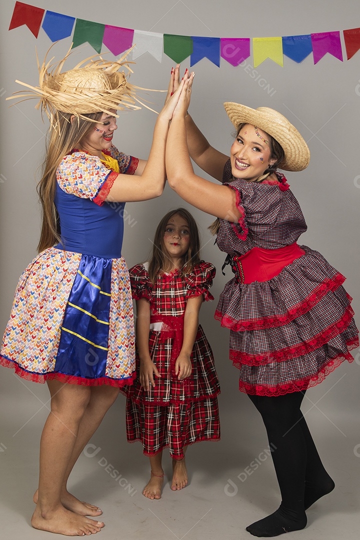 Mulheres jovens celebrando festa junina usando roupas típicas ao lado de uma criança