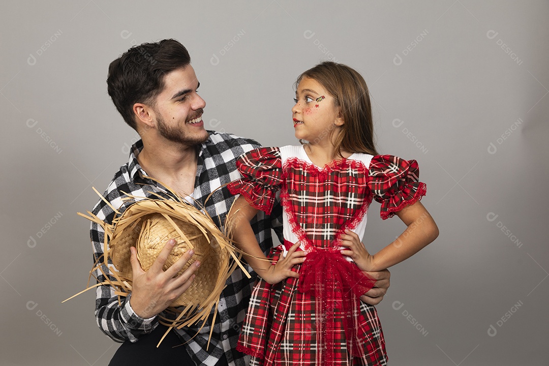Pai jovem usando roupas típicas festa junina ao lado de sua filha