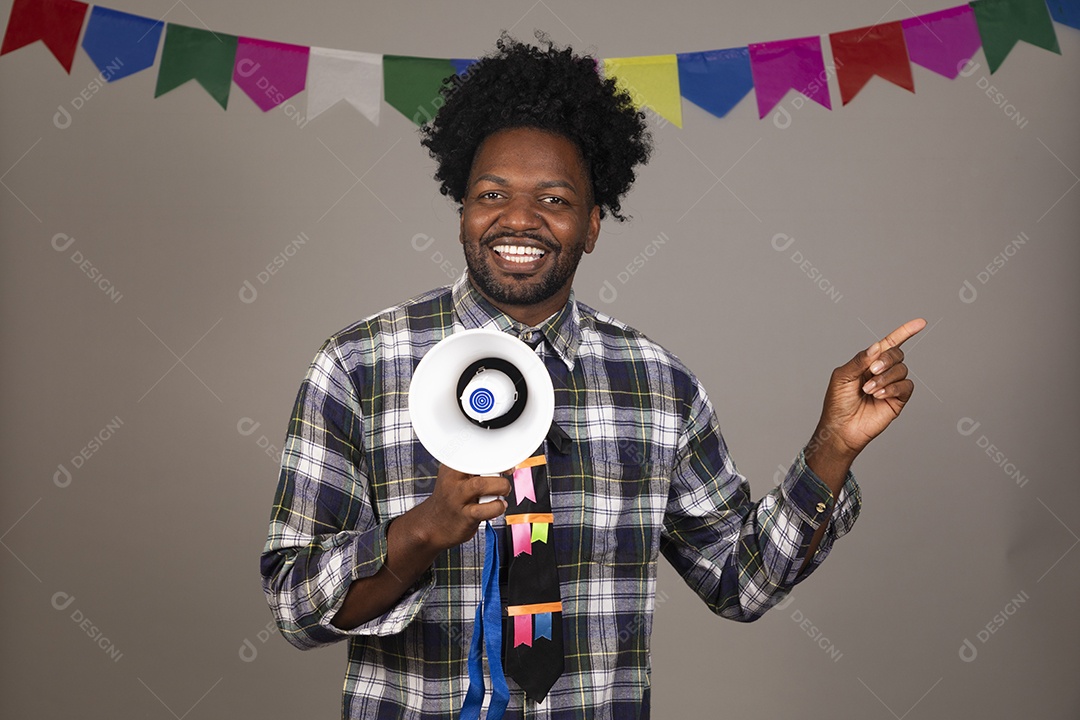 Homem jovem negro usando roupas típicas festa junina sobre fundo isolado usando megafone