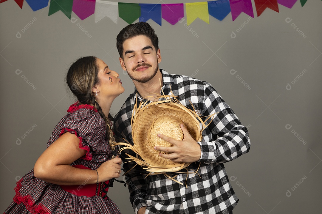Lindo casal de jovens celebrando festa junina usando roupas típicas