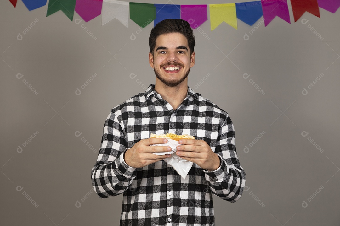 Homem jovem celebrando festa juninas se alimentando sobre fundo isolado