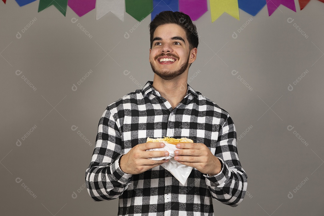Homem jovem celebrando festa juninas se alimentando sobre fundo isolado