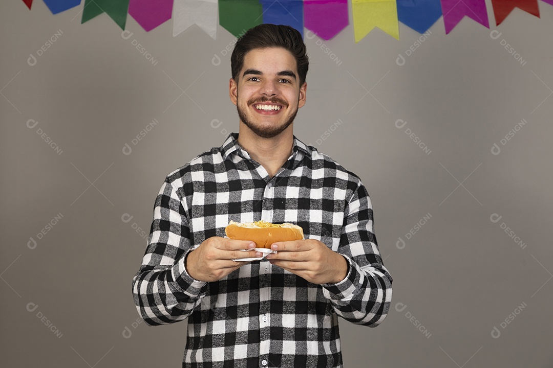 Homem jovem celebrando festa juninas se alimentando sobre fundo isolado