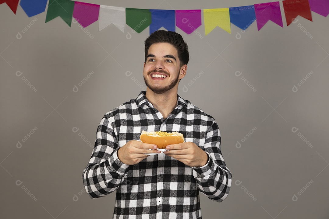 Homem jovem celebrando festa juninas se alimentando sobre fundo isolado
