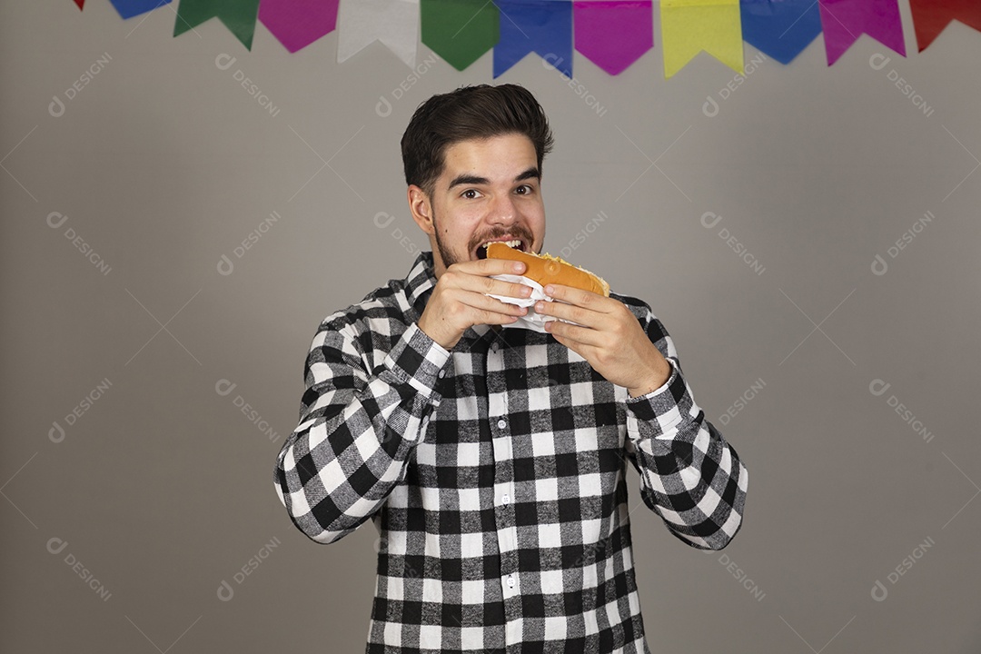 Homem jovem celebrando festa juninas se alimentando sobre fundo isolado
