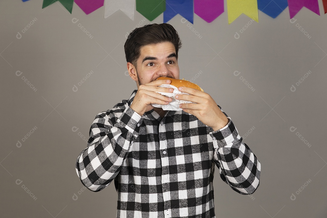 Homem jovem celebrando festa juninas se alimentando sobre fundo isolado