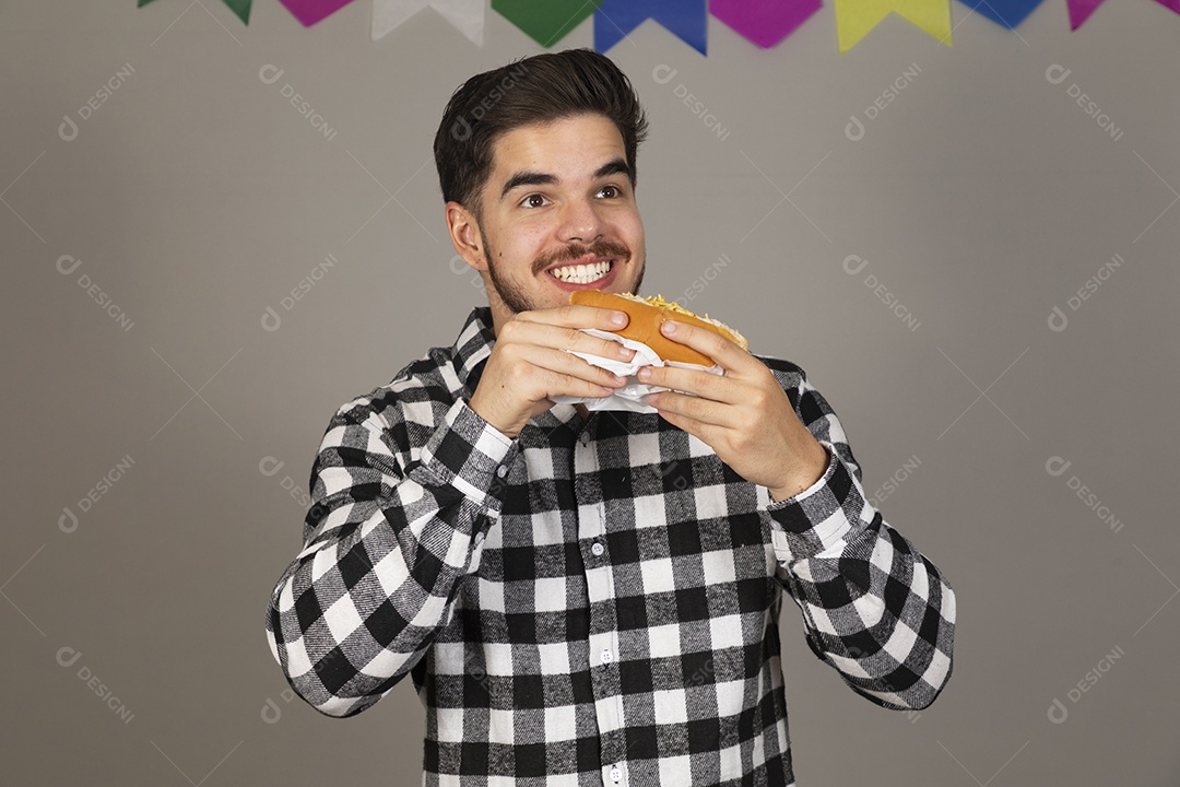 Homem jovem celebrando festa juninas se alimentando sobre fundo isolado