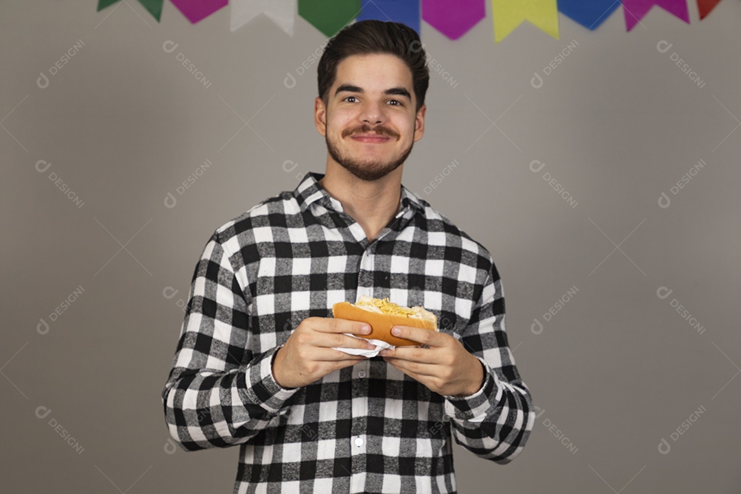 Homem jovem celebrando festa juninas se alimentando sobre fundo isolado