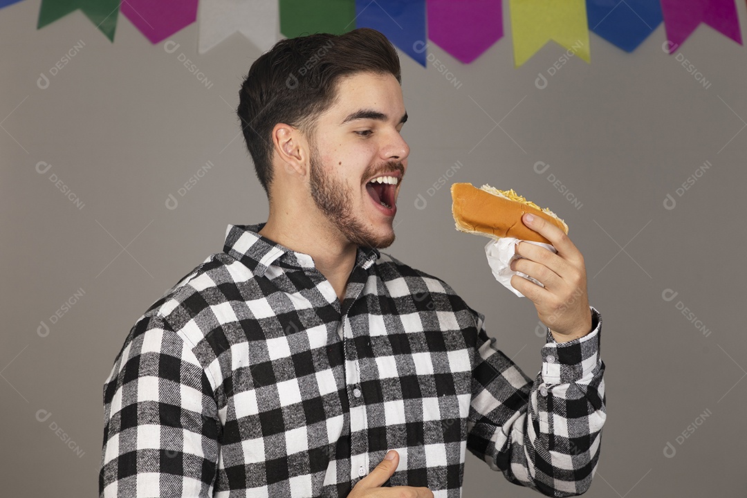 Homem jovem celebrando festa juninas se alimentando sobre fundo isolado