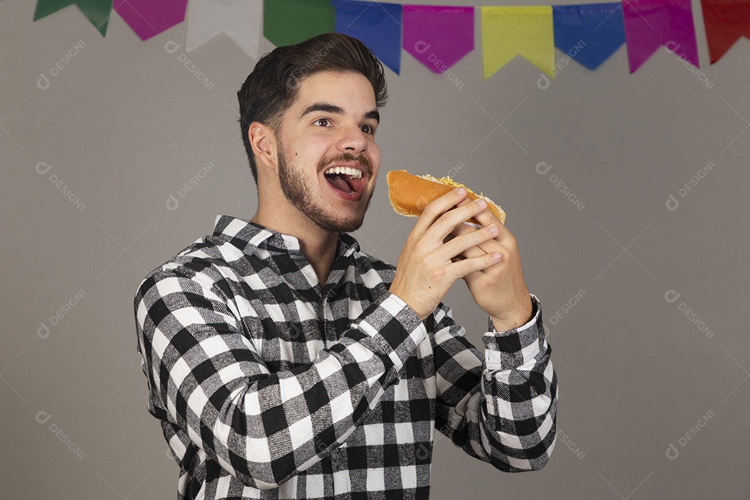 Homem jovem celebrando festa juninas se alimentando sobre fundo isolado