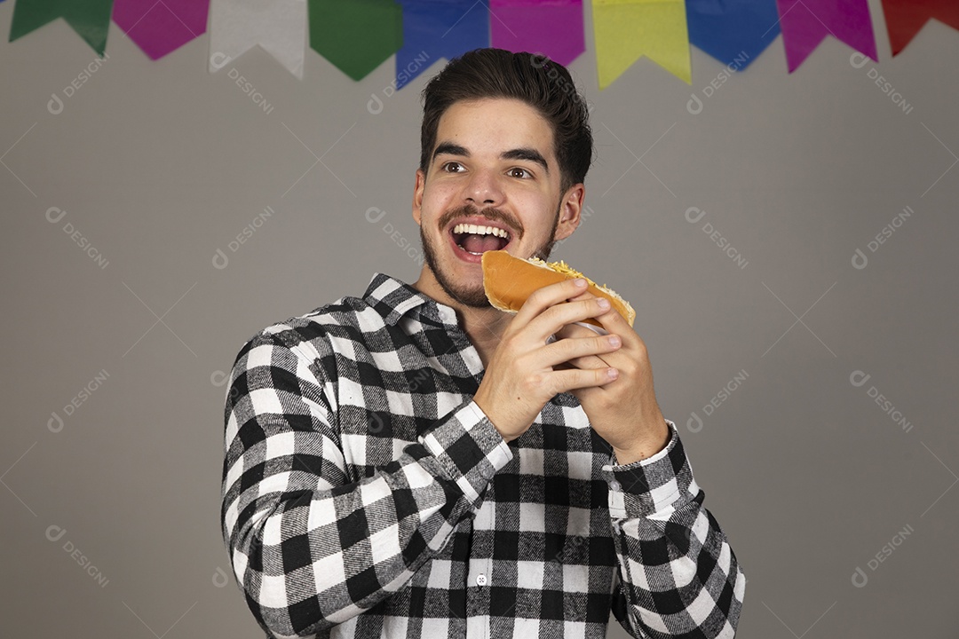 Homem jovem celebrando festa juninas se alimentando sobre fundo isolado