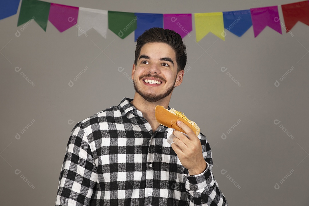 Homem jovem celebrando festa juninas se alimentando sobre fundo isolado