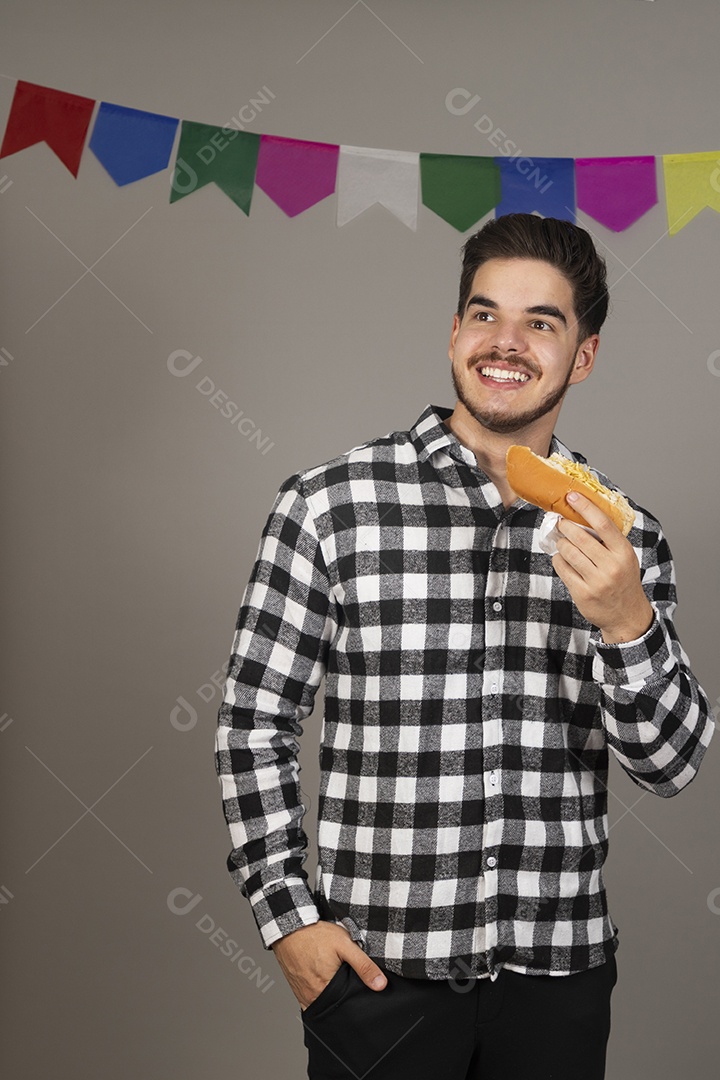 Homem jovem celebrando festa juninas se alimentando sobre fundo isolado