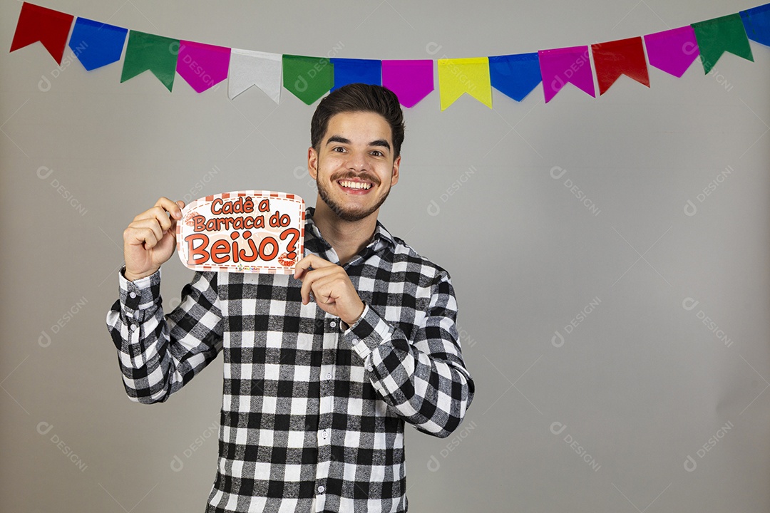Homem jovem usando roupas típicas festa junina segurando placa