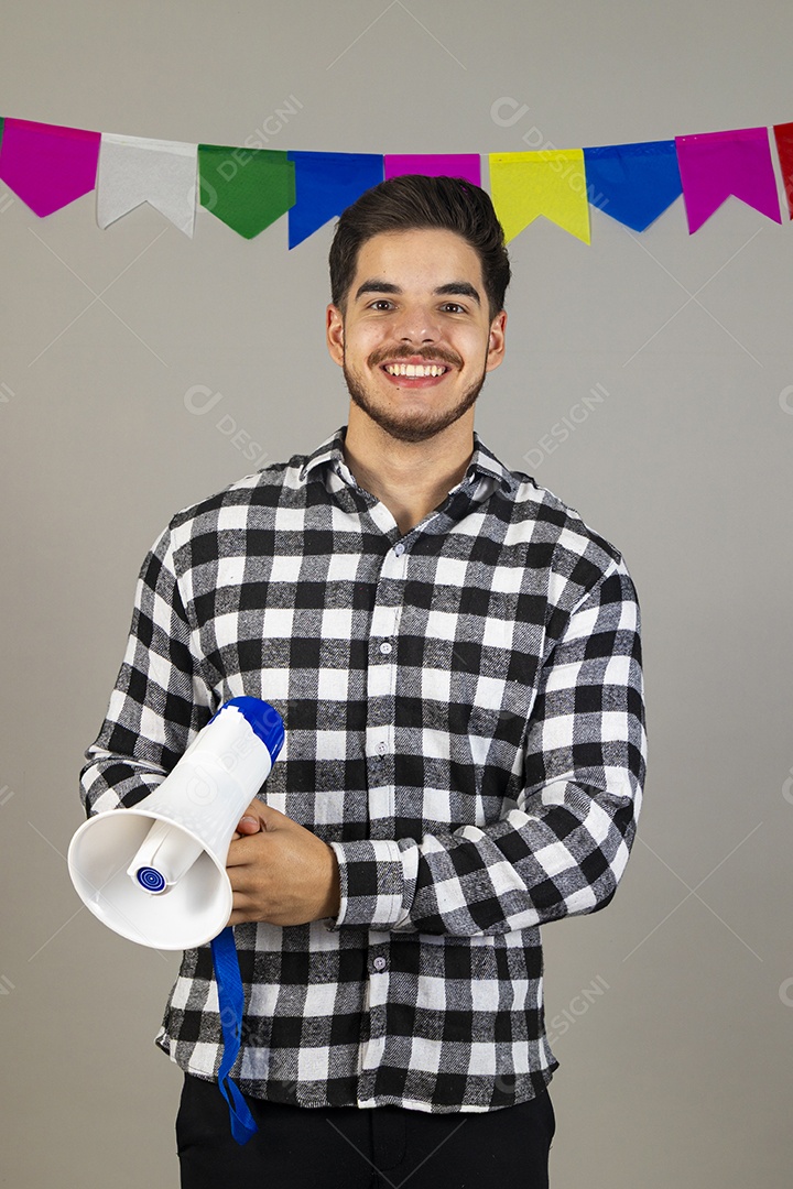 Homem jovem usando roupas típicas festa junina sobre fundo isolado segurando megafone