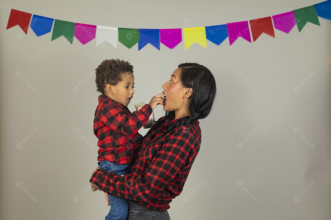 Mãe jovem usando roupas típicas festa junina sobre fundo isolado ao lado de seu filho