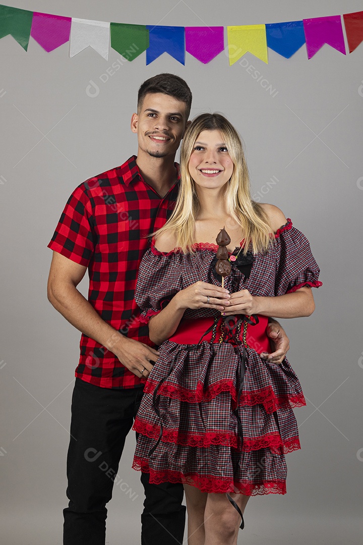 Lindo casal de jovens celebrando festa junina usando roupas típicas de São João