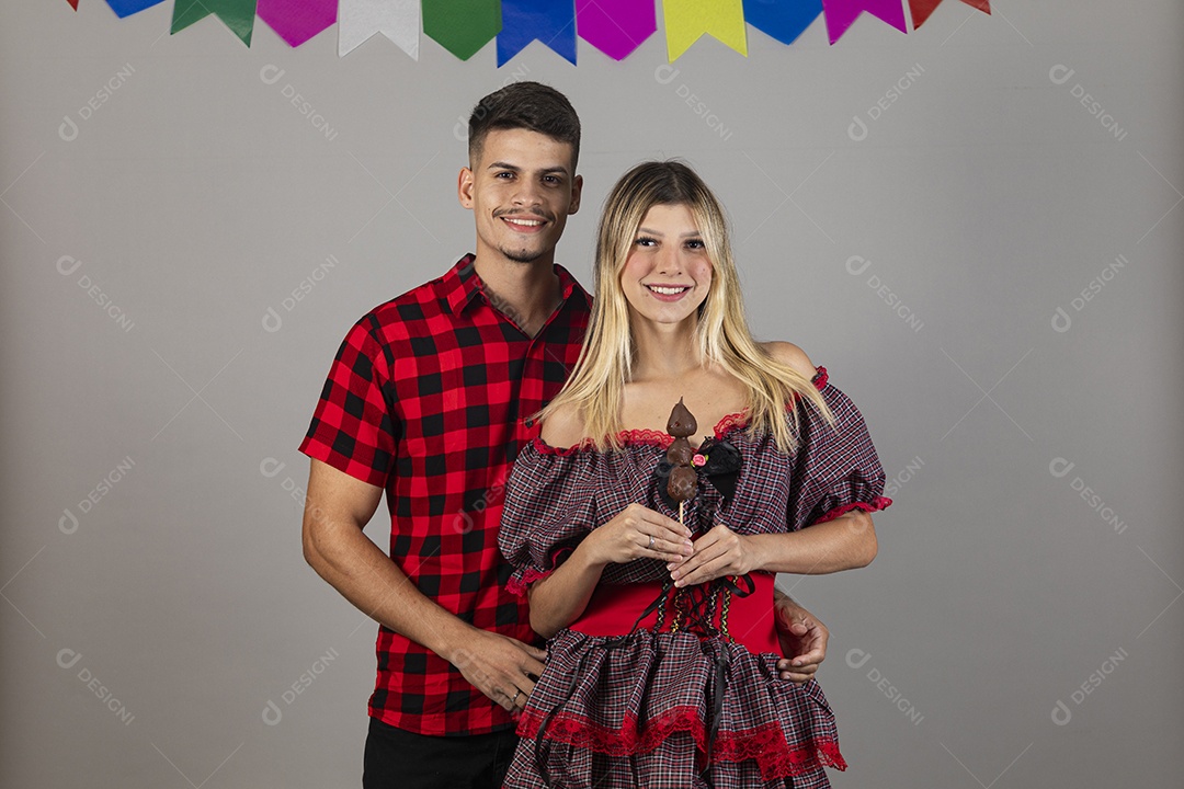 Lindo casal de jovens celebrando festa junina usando roupas típicas de São João