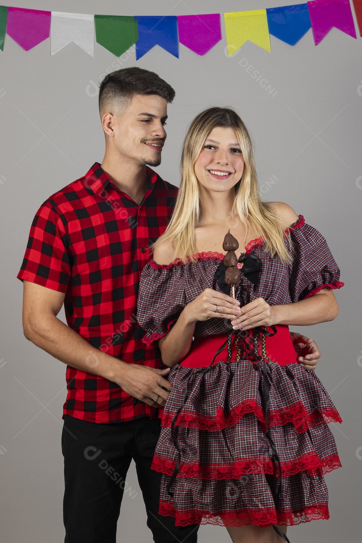 Lindo casal de jovens celebrando festa junina usando roupas típicas de São João