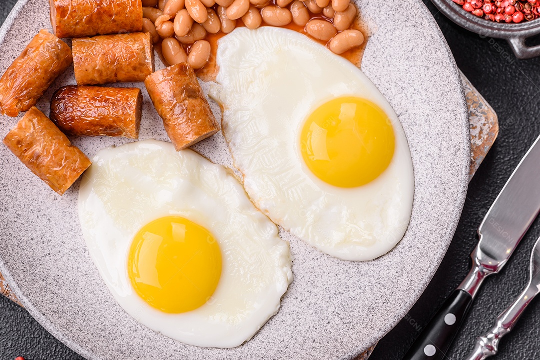 Prato de comida linguiça e ovo frito feijão mesa concreto